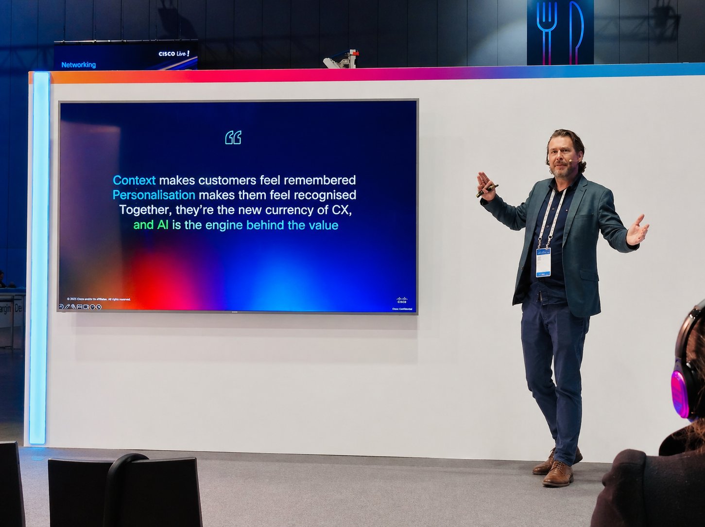 Ben Farrell gesturing to the audience beside a presentation screen at Cisco Live in Melbourne